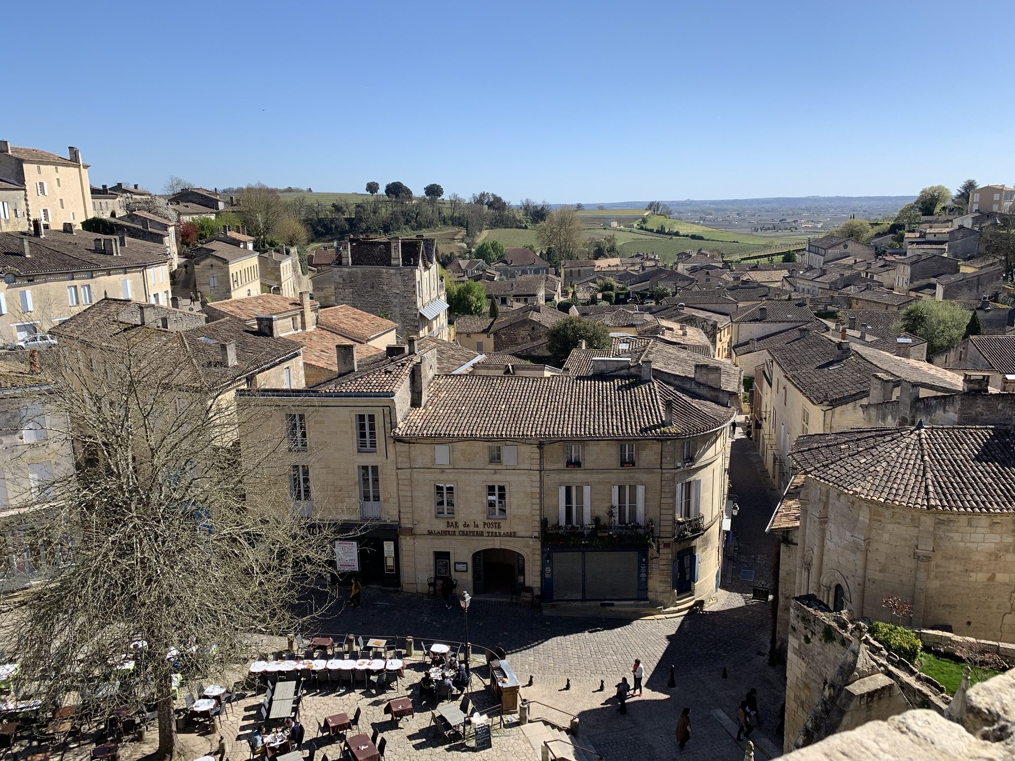 Tile rooftops and the cobbled square of Saint-Émilion, France, with vineyards running to the horizon.