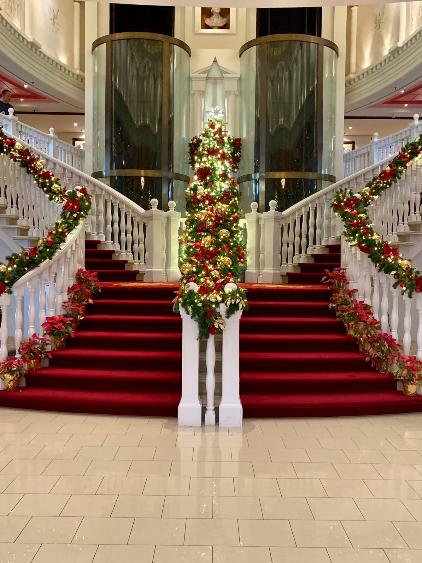 Pride of America's atrium staircase wrapped in garland and poinsettias for the holidays, photographed by Laura North.