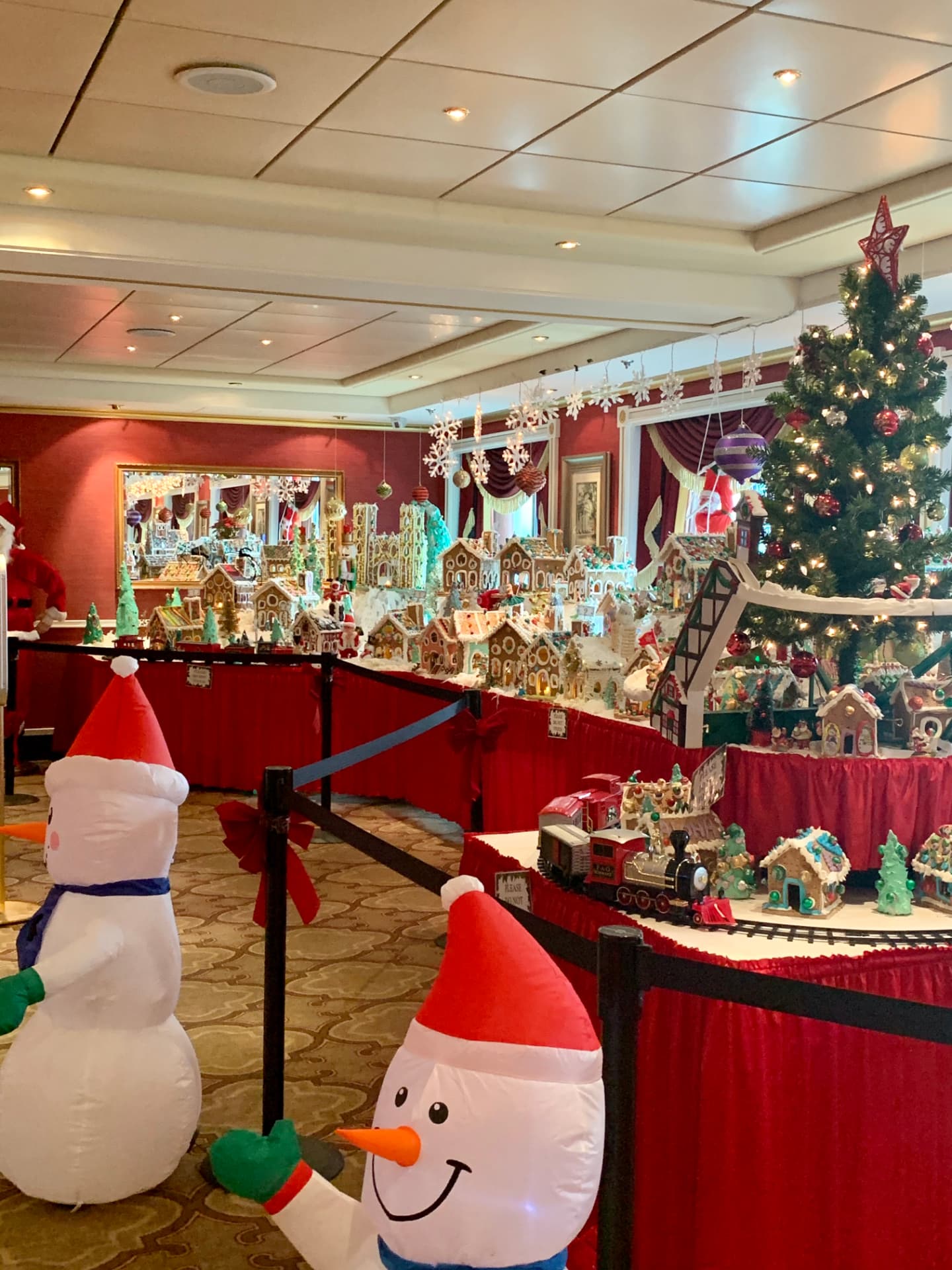 A gingerbread village with a miniature train circling through it aboard Pride of America.
